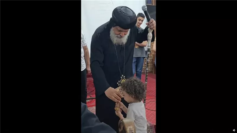 شاهد طفل صغير يهرب بصليب الأنبا ميخائيل أسقف حلوان والمعصرة في مشهد طريف داخل الكنيسة | فيديو